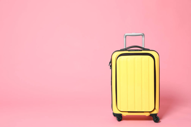 Stylish yellow suitcase on pink background. Space for text - Zdjęcie, obraz