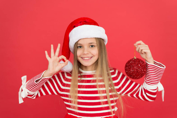 Playful baby. Christmas party. Winter holidays. Playful mood. Christmas celebration ideas. Shine and glitter. Child Santa Claus costume hat. Happy smiling face. Beautiful detail. Positivity concept - Foto, Bild