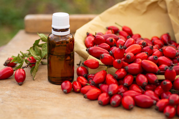 Rose-hips and rose hip seed oil on the wooden table. Rose hip  commonly known as rose hip (Rosa canina).  - Photo, Image