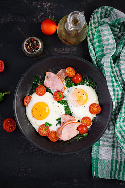 Тарелка с кето диетической пищей. Жареное яйцо, ветчина, шпинат и помидоры. Кето, Палео завтрак. Вид сверху, пространство для копирования
 - Фото, изображение