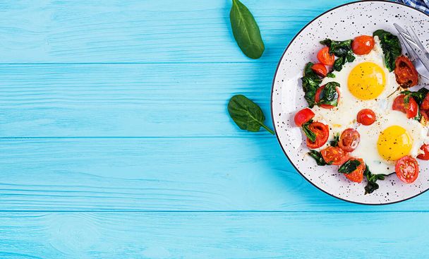 Ontbijt. Ketogeen dieetvoedsel. Gebakken ei, spinazie en tomaten. Keto, paleo ontbijt. Bovenaanzicht, kopieer ruimte - Foto, afbeelding
