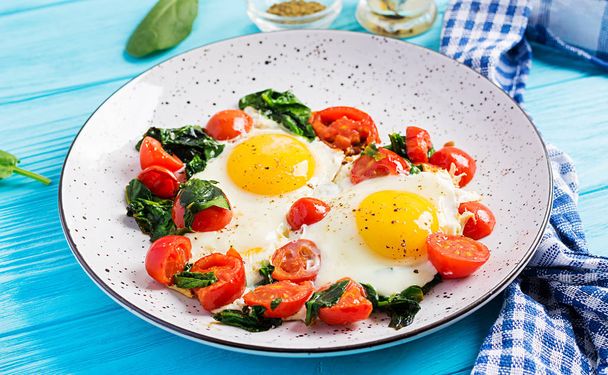 Тарелка с кето диетической пищей. Жареное яйцо, шпинат и помидоры. Кето, палеозавтрак
. - Фото, изображение