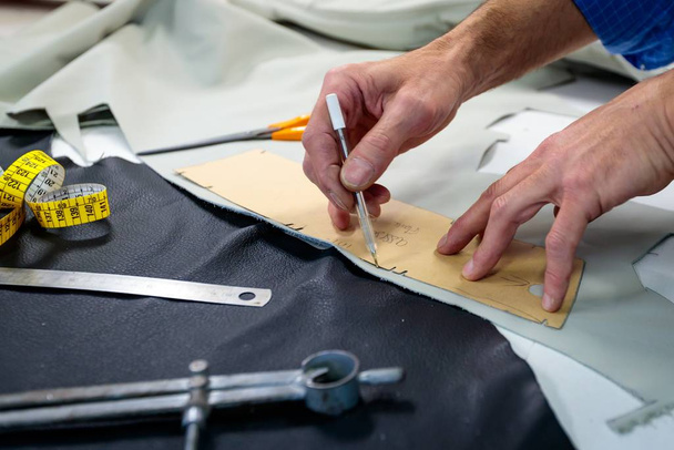 Egy bőrmunkás méréseket végez bőrruházat készítéséhez a stúdióban. - Fotó, kép