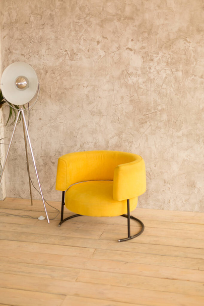 The interior of the room with a yellow chair, retro lamp on the wall with decorative plaster - 写真・画像
