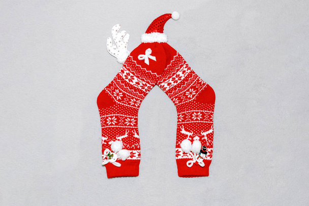 Összetétele karácsonyi piros gyapjú zokni, szarvas szarvak, kalap és hóember egy szürke kockás. Karácsonyi koncepció, ajándékok, party, hangulatos otthon. - Fotó, kép