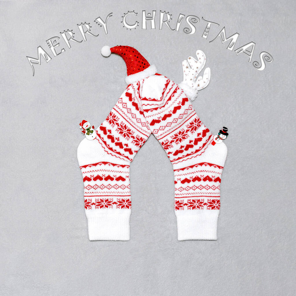 Beyaz Noel çorapları, geyik boynuzları, şapka ve kardan adamların gri bir ekose üzerinde "Mutlu Noeller" yazılı hali. Noel konsepti, hediyeler, parti, rahat ev. - Fotoğraf, Görsel
