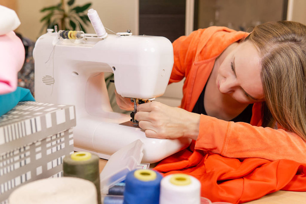 vrouwelijke kleermaker probeert om de naald in een naaimachine - Foto, afbeelding
