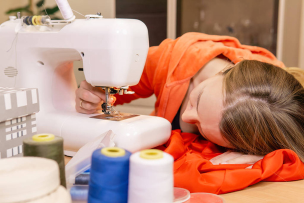 жіноча швачка намагається встановити голку в швейній машинці
 - Фото, зображення
