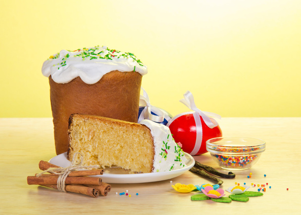 Part of an Easter cake on a saucer, eggs, marzipan on a table, on a yellow background - Foto, Imagen