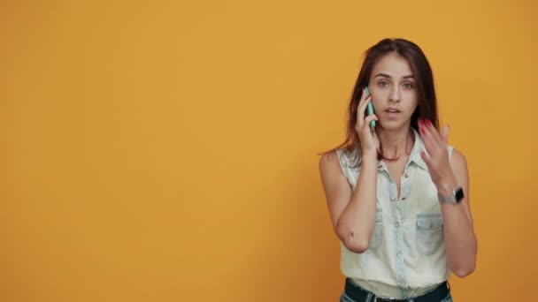 Woman keeping hand on mouth, holding telephone, speaking about something - Filmmaterial, Video