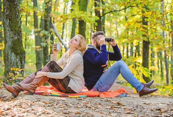 Happy loving couple relaxing in park together. Couple in love tourists relaxing picnic blanket. Man with binoculars and woman with metal mug enjoy nature park. Park date. Relaxing in park together - Foto, afbeelding