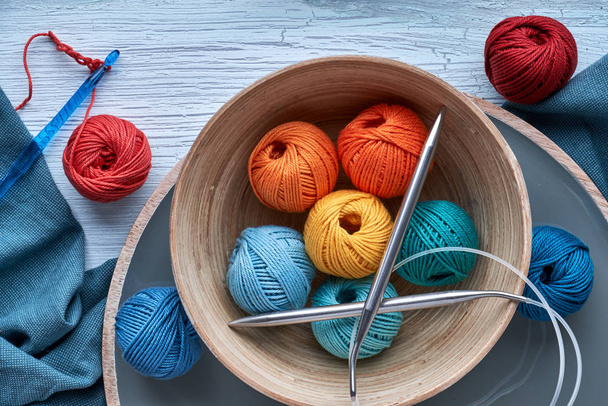 Top view of various yarn balls and latch hook on textured background - Foto, afbeelding