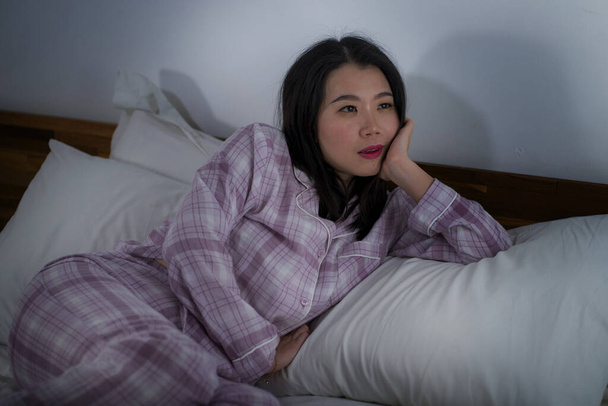 dramatic lifestyle portrait of young attractive sad and depressed Asian Korean woman on bed awake at night feeling stressed and lost suffering depression problem in sadness  - Foto, afbeelding