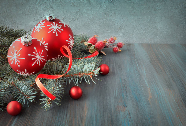 Wooden background with Christmas tree twigs decorated with Xmas baubles, ribon and frosted berries. Space for your text, filtered image. - 写真・画像