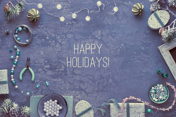 Creative diy craft hobby. Making handmade jewelry for friends as Christmas gifts. Flat lay on dark fluid art acrylic board with text "Happy Holidays". - Fotoğraf, Görsel