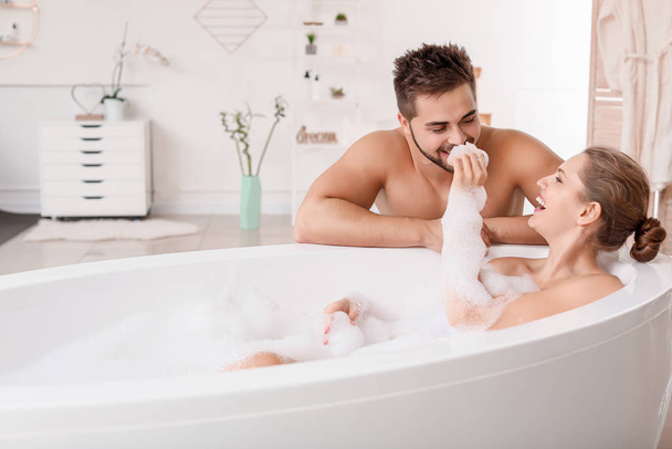 Όμορφη νεαρή γυναίκα περνάει χρόνο με τον άντρα της ενώ κάνει μπάνιο. - Φωτογραφία, εικόνα