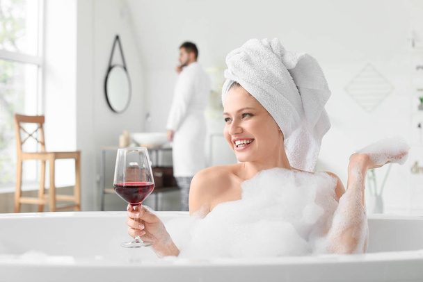 Όμορφη νεαρή γυναίκα πίνει κρασί ενώ κάνει μπάνιο - Φωτογραφία, εικόνα