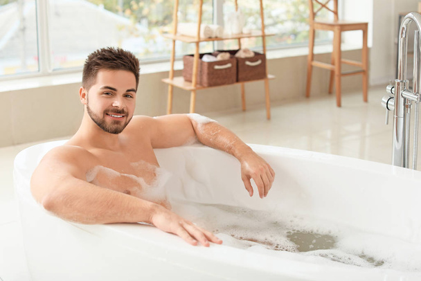 Handsome young man taking bath at home - Foto, afbeelding