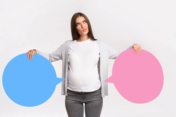 Chica embarazada sosteniendo burbujas de habla azul y rosa cerca del vientre
 - Foto, imagen