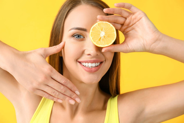 Gyönyörű fiatal nő citrommal színes háttér - Fotó, kép