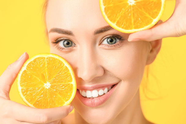 Mulher bonita com fatias de laranja no fundo de cor, close-up
 - Foto, Imagem