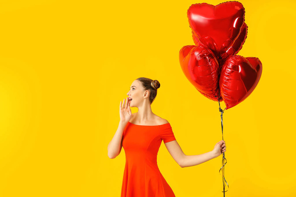 Beautiful young woman with heart-shaped balloons on color background - Photo, Image