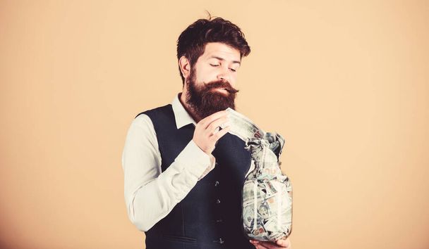 Start saving for your retirement as early as possible. Establish your budget. Businessman with his dollar savings. Security and cash money savings. Man bearded guy hold jar full of cash savings - Foto, afbeelding