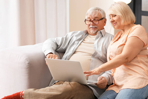 Couple d'âge mûr avec ordinateur portable se reposant à la maison
 - Photo, image