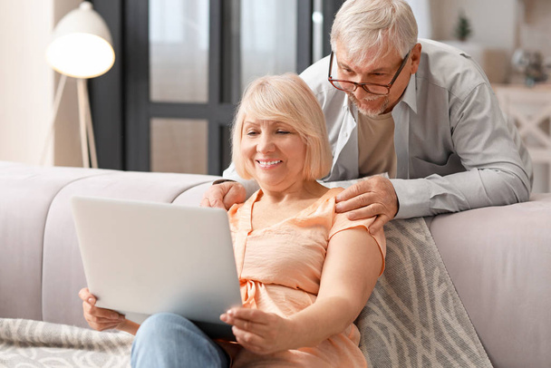 Couple d'âge mûr avec ordinateur portable se reposant à la maison
 - Photo, image
