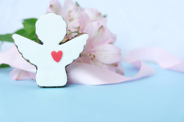 Cookies in the shape of an angel with a pink ribbon on a pink background. - 写真・画像