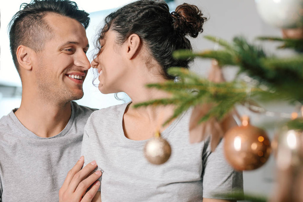 Happy young couple near Christmas tree at home - Foto, Imagen