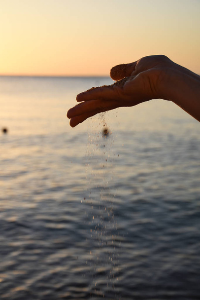 άμμο ρίξει το χέρι στο φόντο της θάλασσας - Φωτογραφία, εικόνα