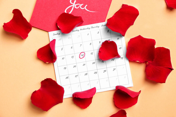 Calendário com data marcada do Dia dos Namorados, cartão e pétalas de rosa no fundo de cor
 - Foto, Imagem