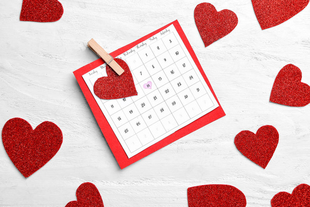 Calendário com data marcada do Dia dos Namorados e corações vermelhos no fundo de madeira branca
 - Foto, Imagem