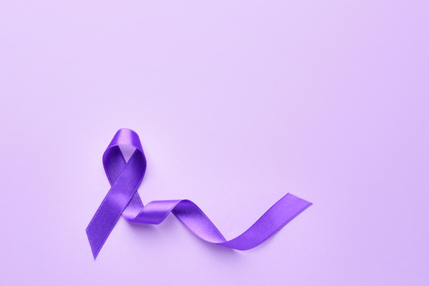 Фіолетова стрічка - символ Всесвітнього дня раку на кольоровому тлі. - Фото, зображення