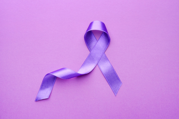 Purple ribbon as symbol of World Cancer Day on color background - Foto, Imagen