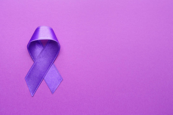 Purple ribbon as symbol of World Cancer Day on color background - Fotografie, Obrázek