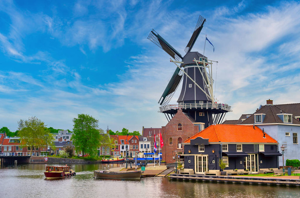 Un molino de viento a lo largo de los canales en Haarlem, Países Bajos en un día despejado
. - Foto, imagen