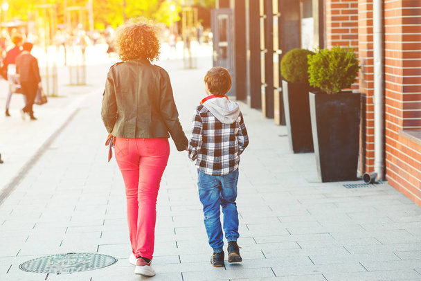 Šťastná matka a syn procházející se po ulici, pohled zezadu. Rodina, mateřství a vztah - Fotografie, Obrázek