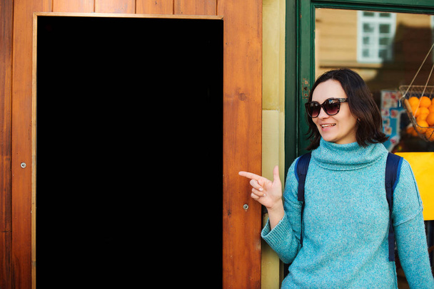 Γυναίκα ταξιδιώτισσα δείχνει άδεια μαύρη πινακίδα. Μαθήτρια που περπατάει στο δρόμο της πόλης. Αγορά του δρόμου - Φωτογραφία, εικόνα