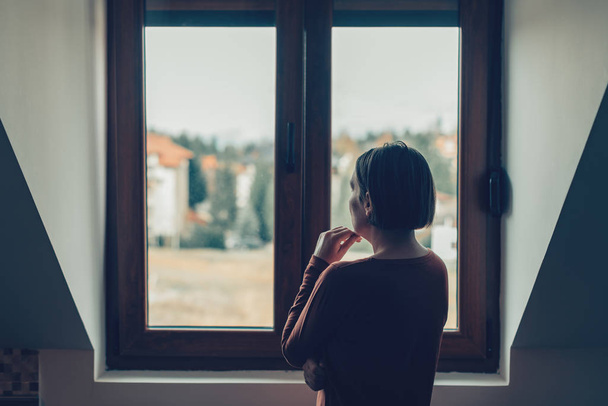 Sad woman looking out of the window - Φωτογραφία, εικόνα