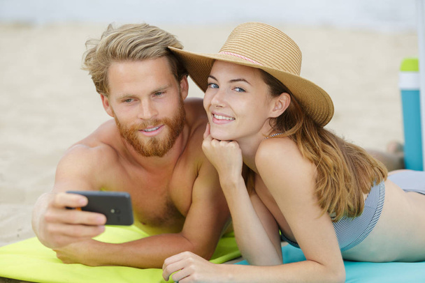 couple taking selfie on beach woman looking to camera - Фото, зображення