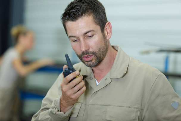 man with a walkie talkie or portable radio transceiver - Foto, afbeelding