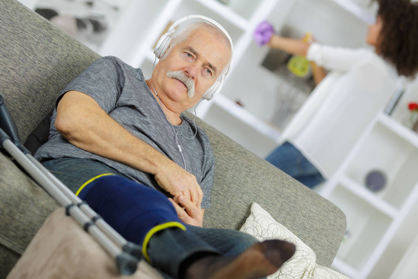 injured senior man listening to music at home - Фото, зображення