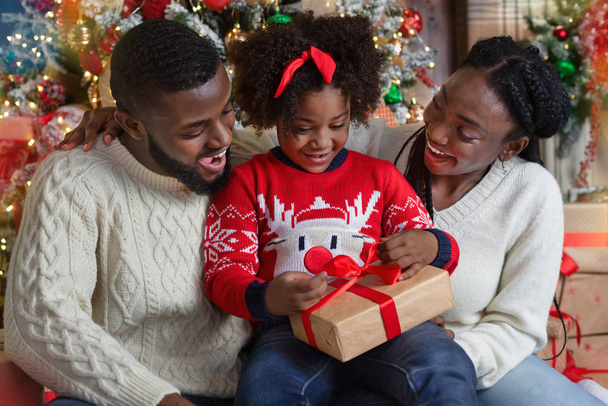 Cute little black girl opening Christmas gift with her parents - Photo, Image