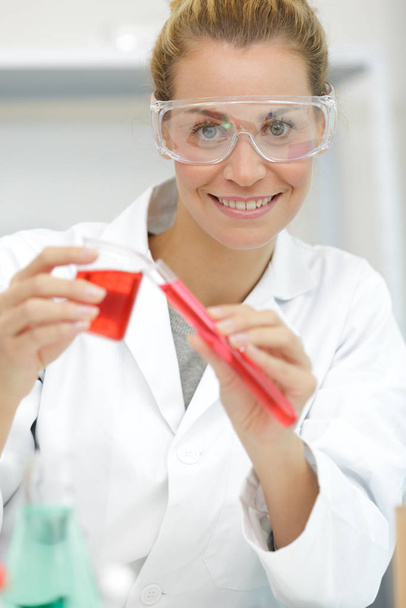 positive minded woman smiling while looking at a test tube - 写真・画像