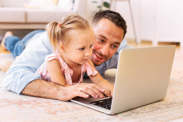 Père enseignant à sa fille comment utiliser un ordinateur portable
 - Photo, image
