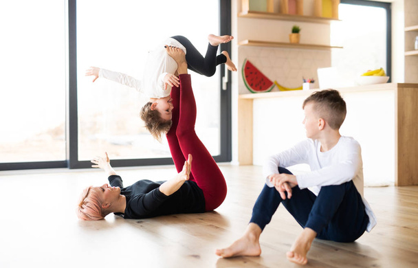 A young woman with two children playing on the floor, having fun. - Photo, Image