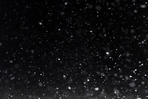 Ночью выпадает снег. Огни боке на черном фоне, летающие снежинки в воздухе. Наложение текстуры. Снежная буря
 - Фото, изображение