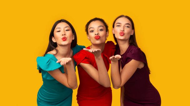 Trois belles filles envoyant des baisers d'air debout dans le studio, panorama
 - Photo, image